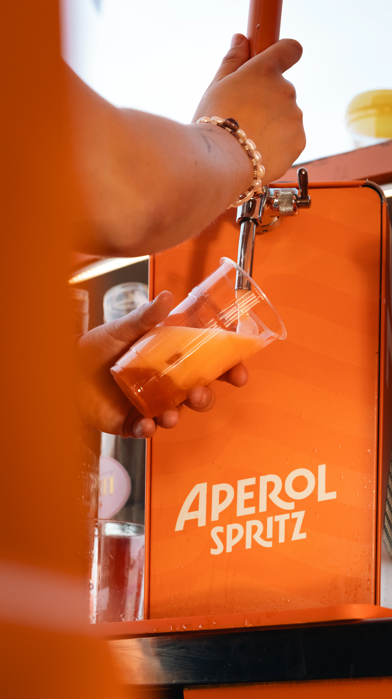 Une main prend un spritz au comptoir Aperol