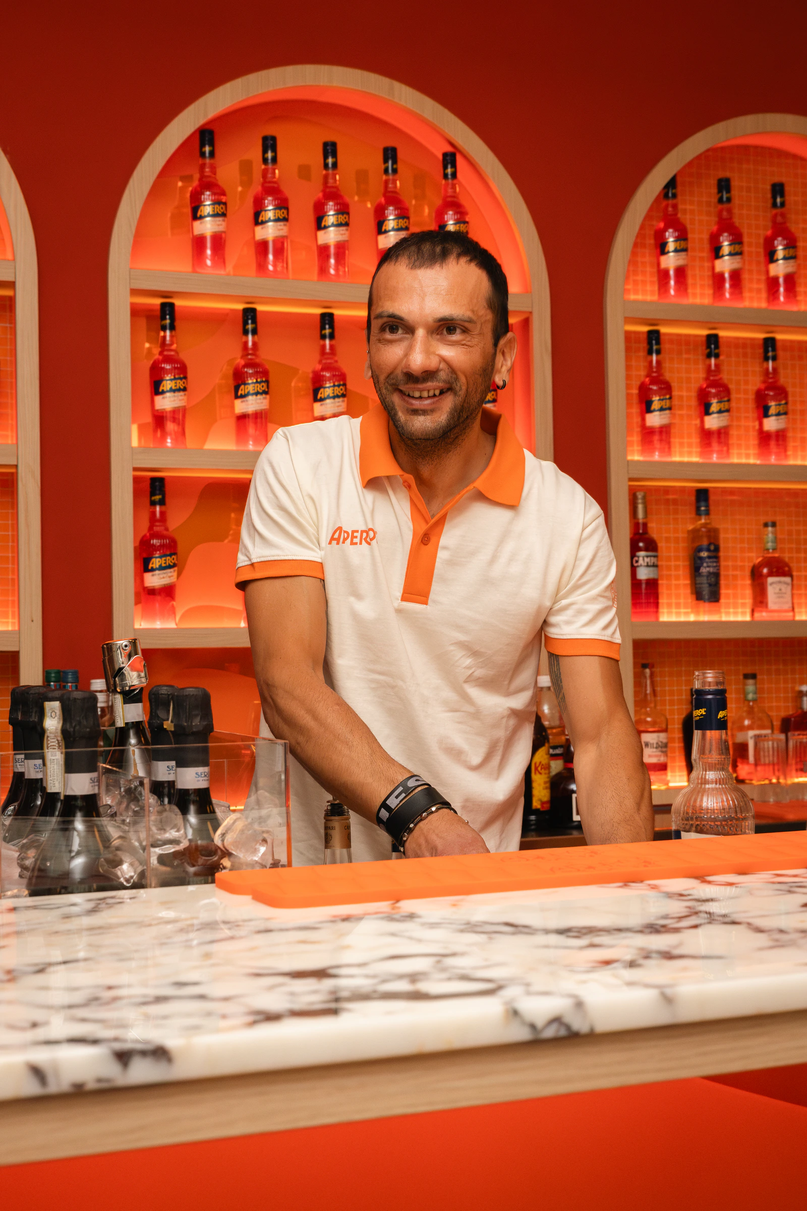 Ein Barkeeper an der Marmortheke, hinter ihm die Flaschenwand