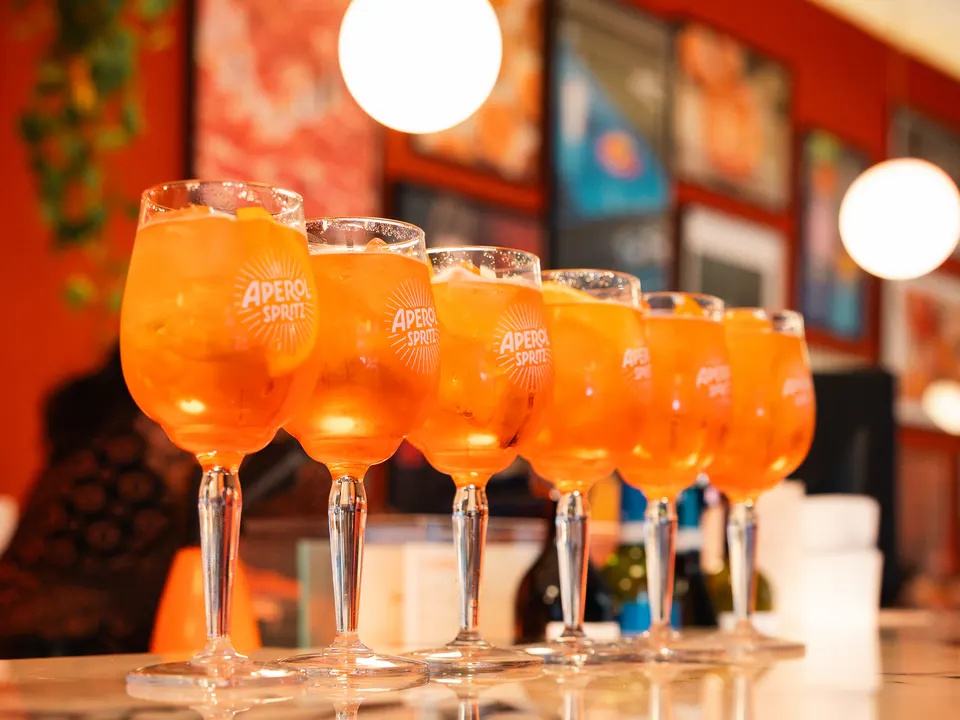 Eine Reihe Aperol Spritz auf der Bar, bereit zum Servieren