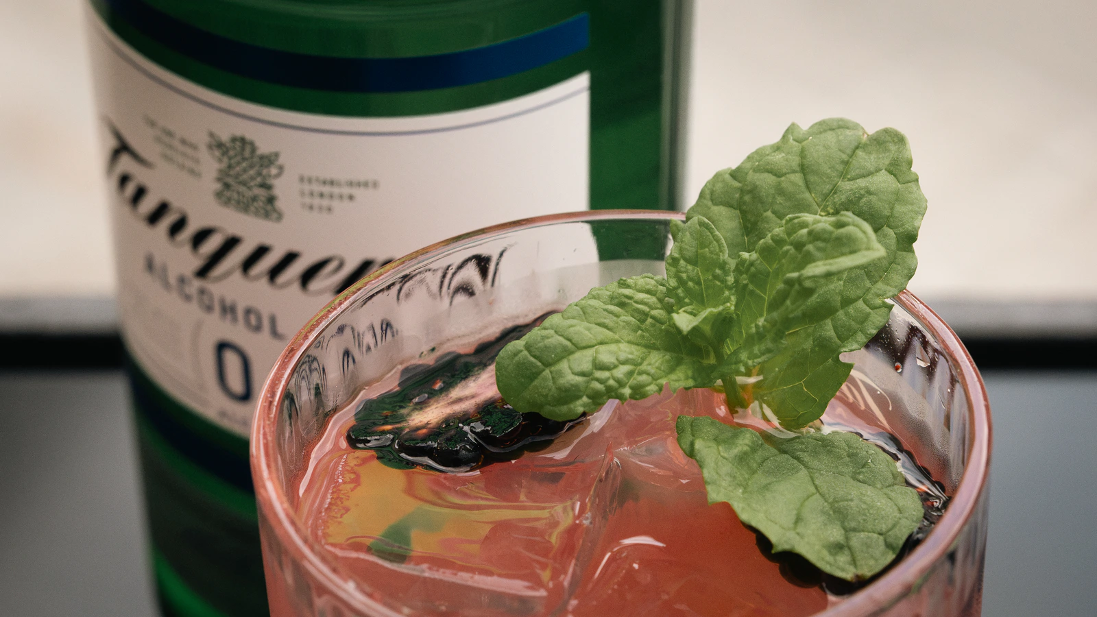 Ein Cocktail neben einer Ginflasche, aus der Nähe fotografiert