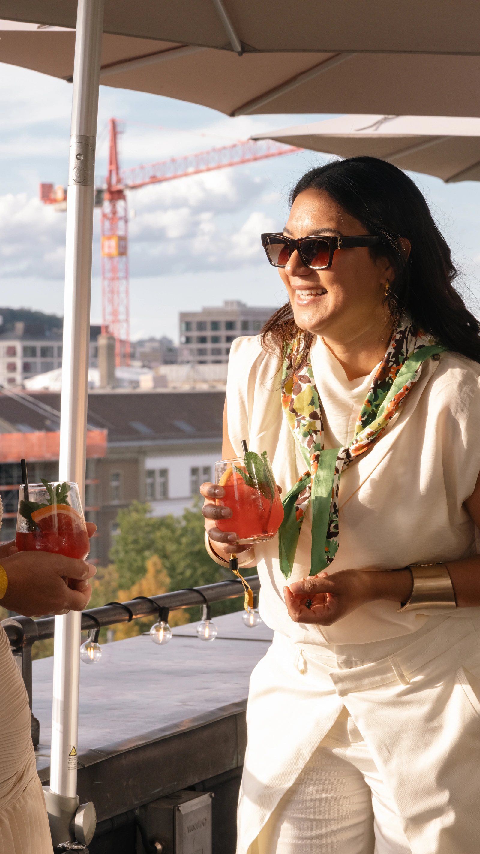 Ein Gast in Weiss mit Sonnenbrille auf der Terrasse, dahinter Dächer und ein Kran