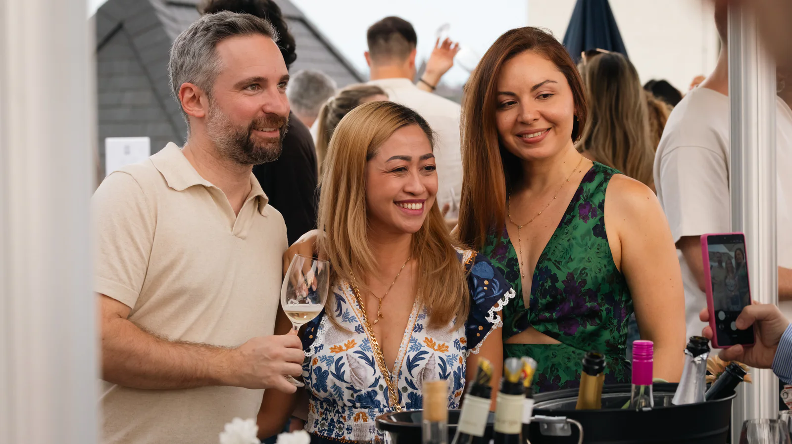 Trois invités rient ensemble, verre de vin à la main, au comptoir de dégustation