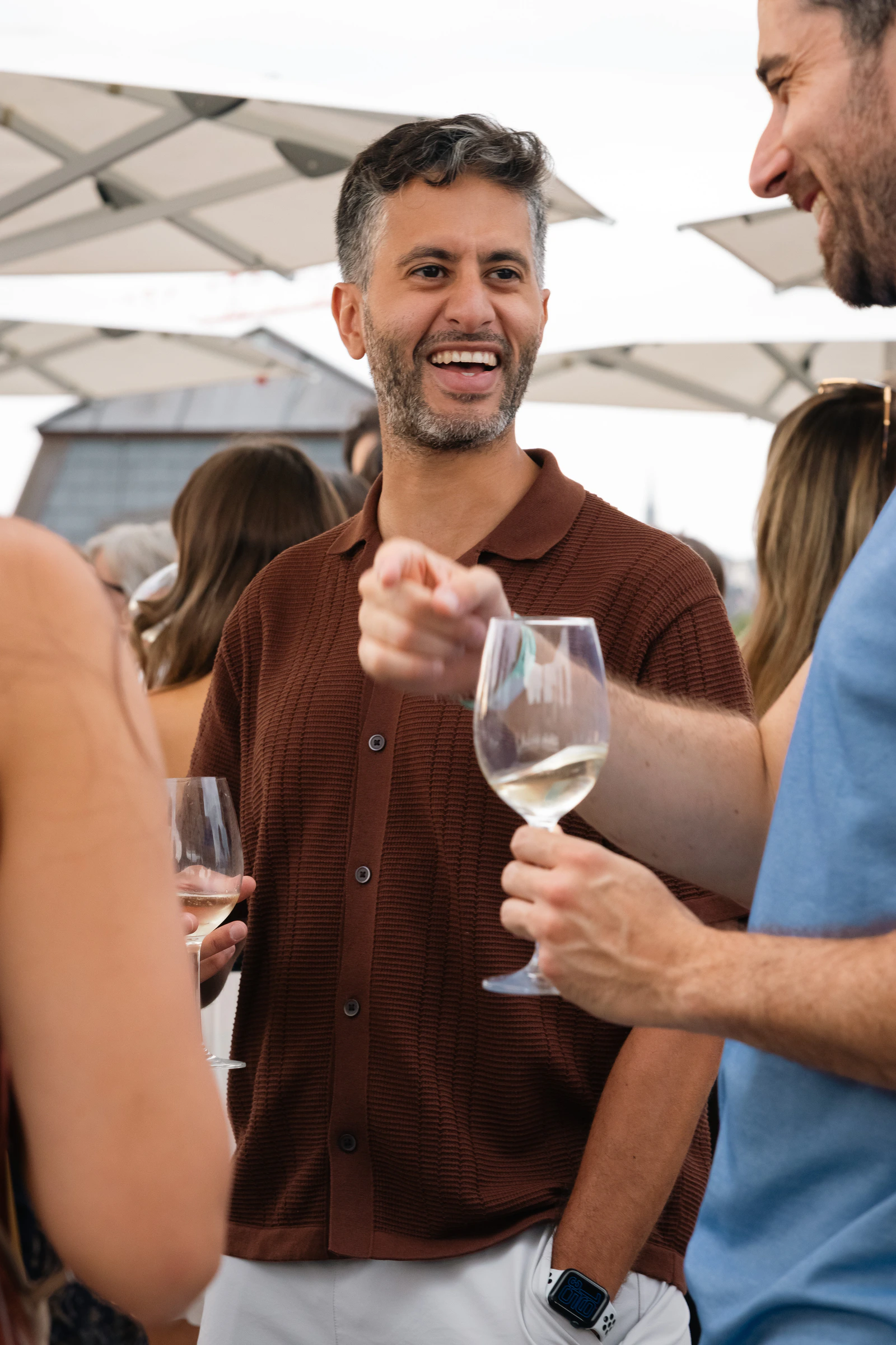 Un invité lève son verre de vin blanc vers quelqu’un hors champ