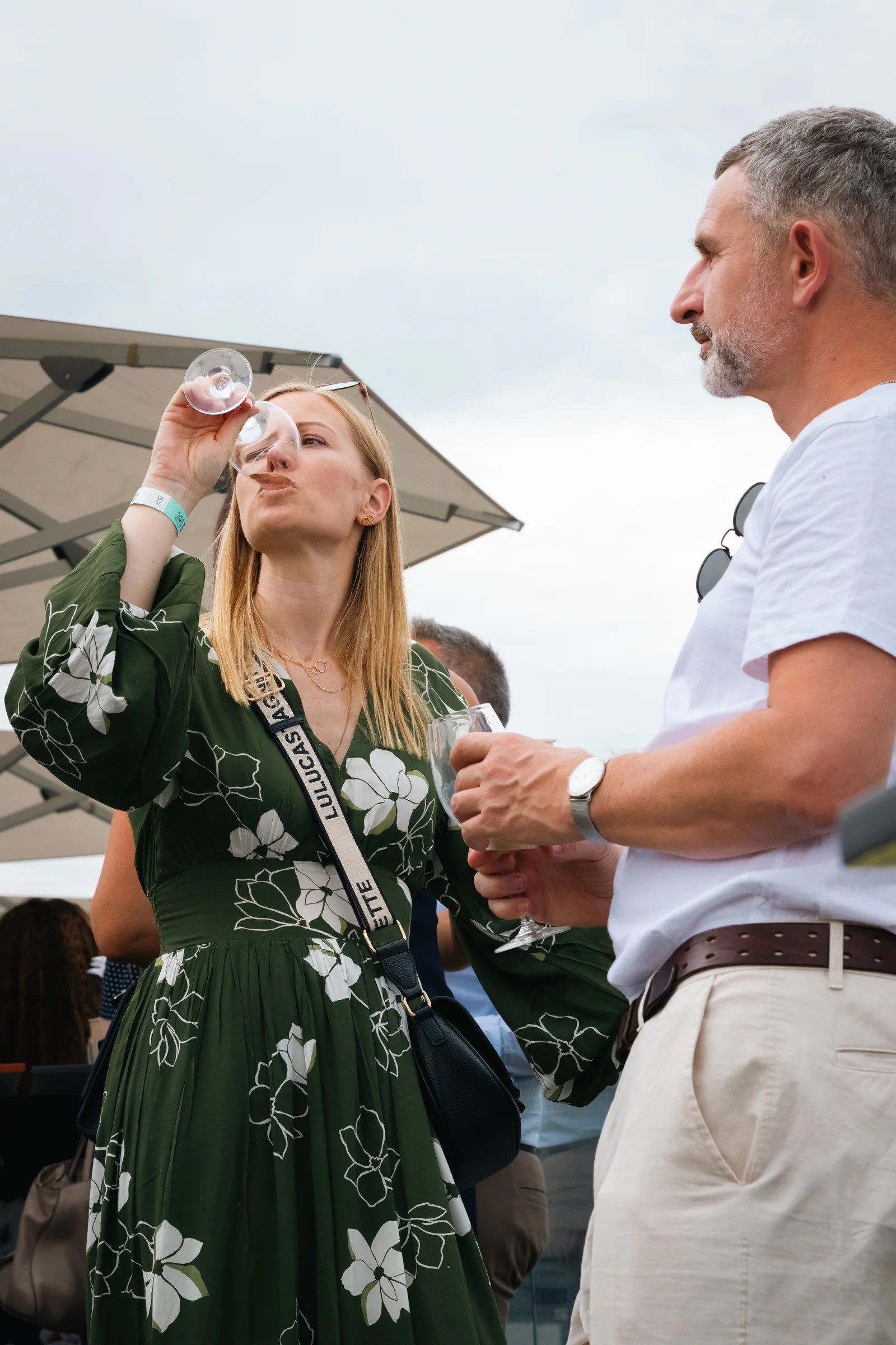 Une invitée déguste près du stand, le verre aux lèvres